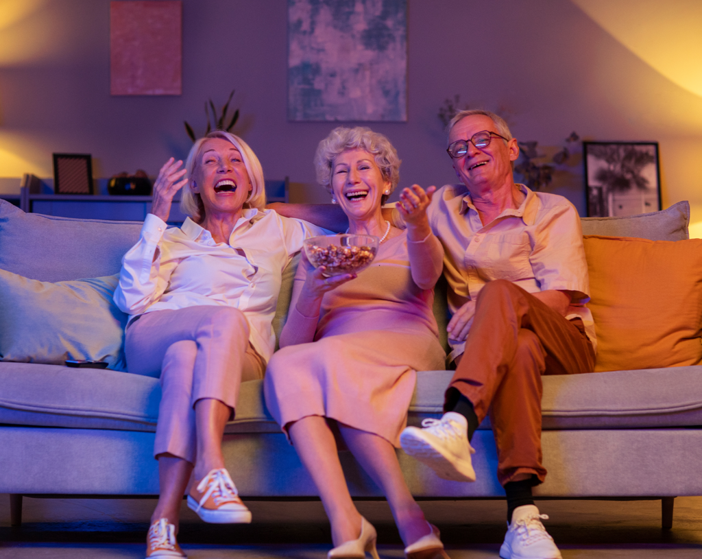 Image of three seniors having fun together while sitting on a sofa